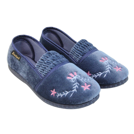 Womens full slippers. Full back slippers in a loafer style. With light blue velour uppers and an embroidered pale blue and pink flower detail. Ruched velour elasticated gusset. Blue textile lining and piping around the collar. Blue firm sole. Both feet together at an angle.