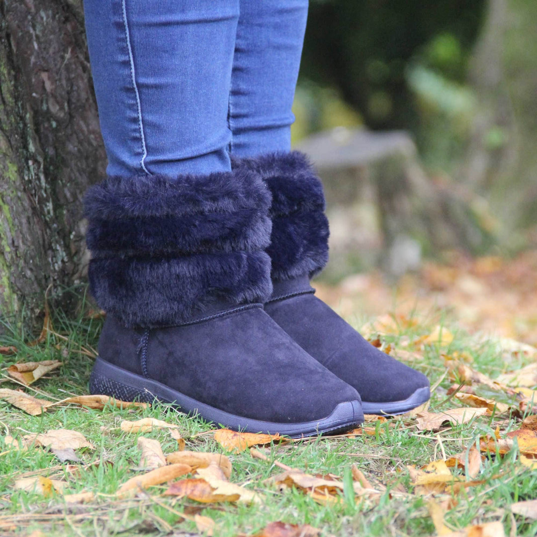 Womens Faux Fur Lined Winter Boots - Navy Blue ankle boots with slight wedge heel, suede effect upper with soft faux fur cuff, scuff resistant bumper to front. Model shot in Autumn.