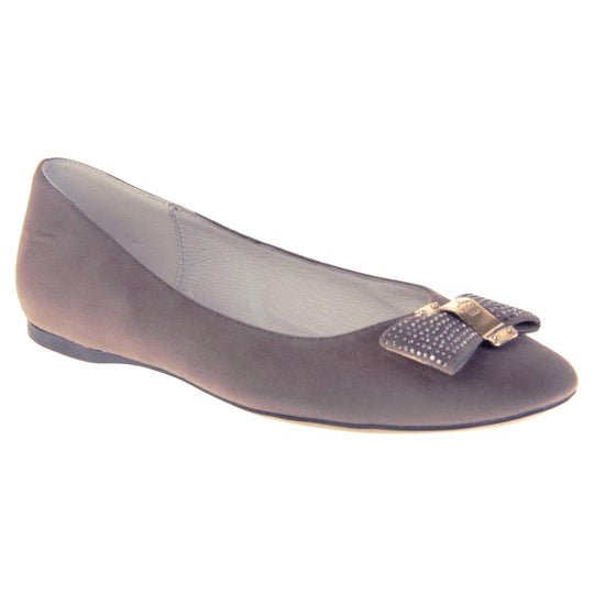 Women's grey flats. Ballet style shoes with a grey faux suede upper. Grey bow detail to the top with diamantes covering it and a gold coloured metal loop round the middle. Cream leather lining and black sole. Right foot at an angle.