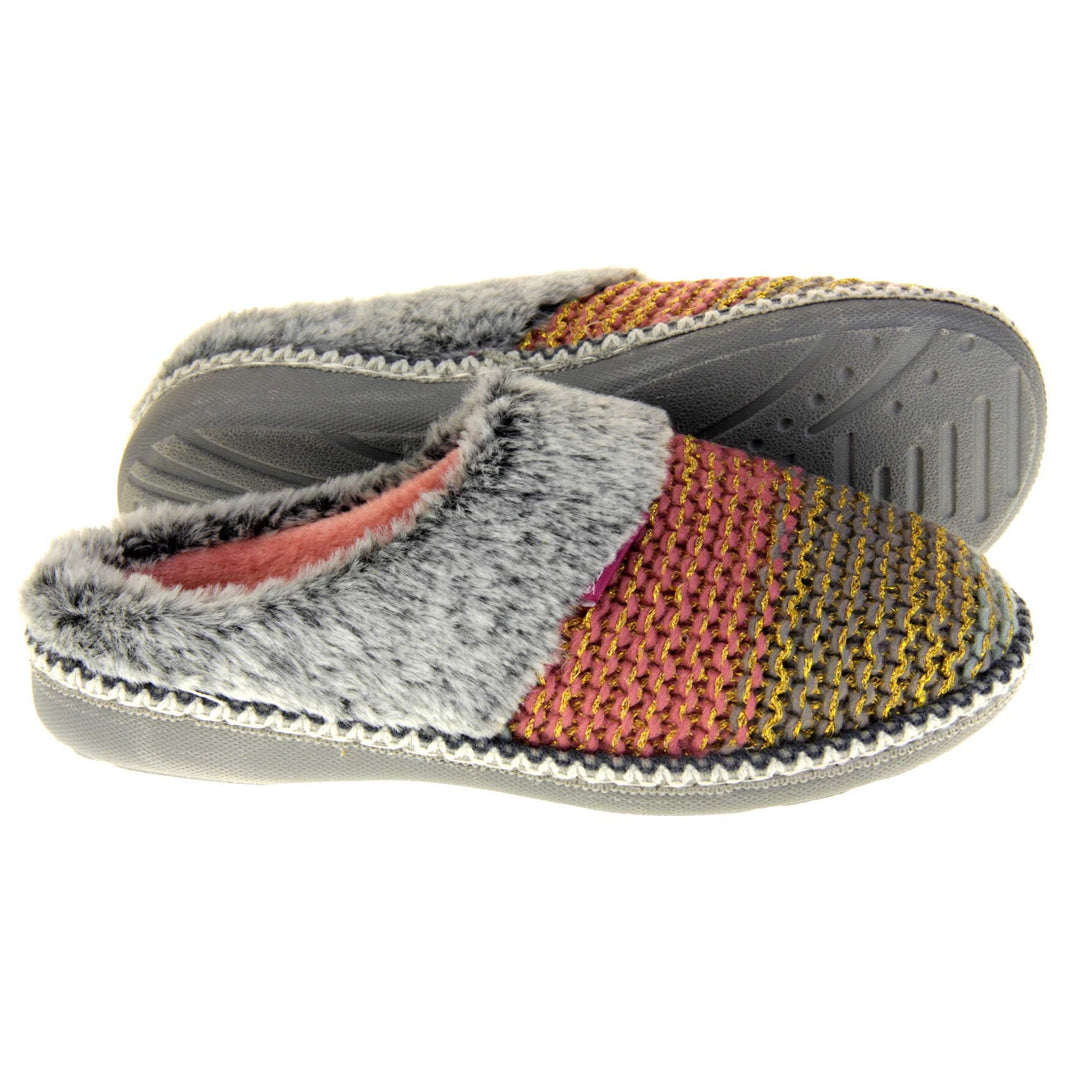 Womens knit slippers. Mule style slippers with pink and blue knit uppers with metallic gold thread running through. Grey faux fur collar. Pink textile lining and firm grey outsole with grip on the bottom. Both feet from a side profile with the left foot on its side behind the the right foot to show the sole.