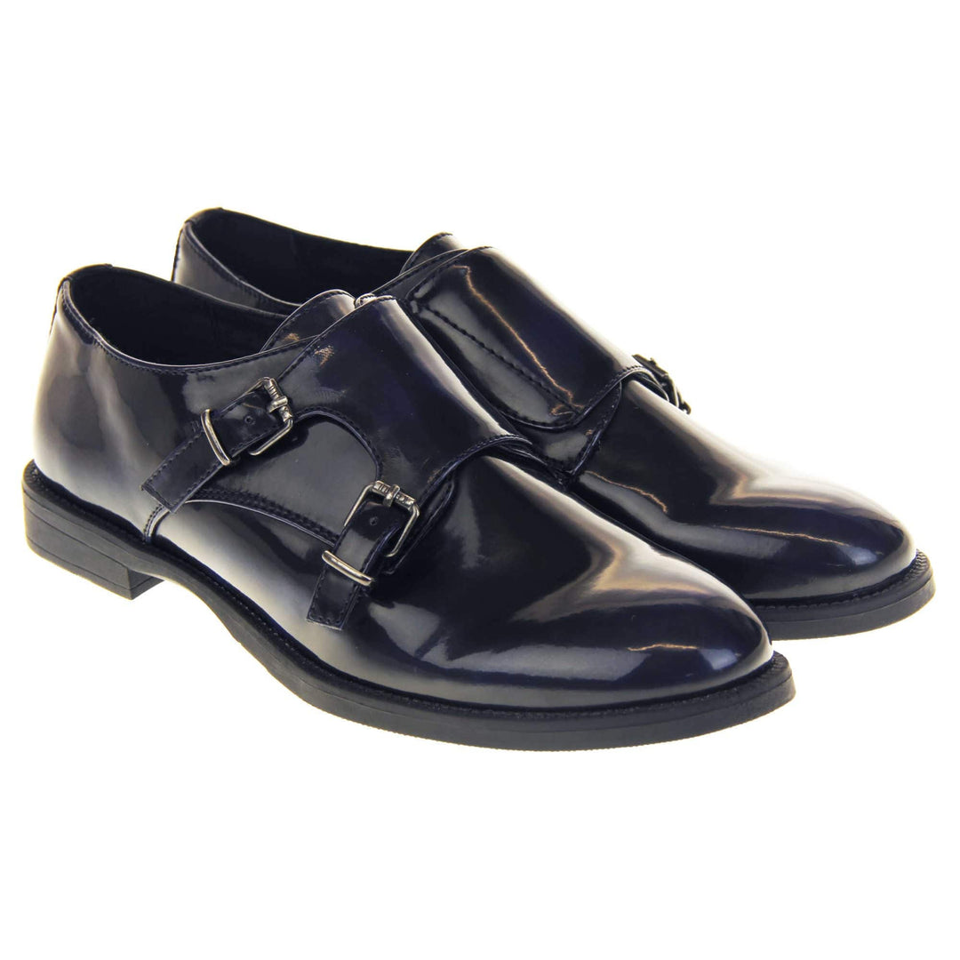 Womens leather brogues. Loafer shoes in a Brogue style with a dark blue faux leather upper. Faux leather flap over the top fastened with double buckles. Real leather lining. Black sole with a slight heel. Both feet together at a slight angle.