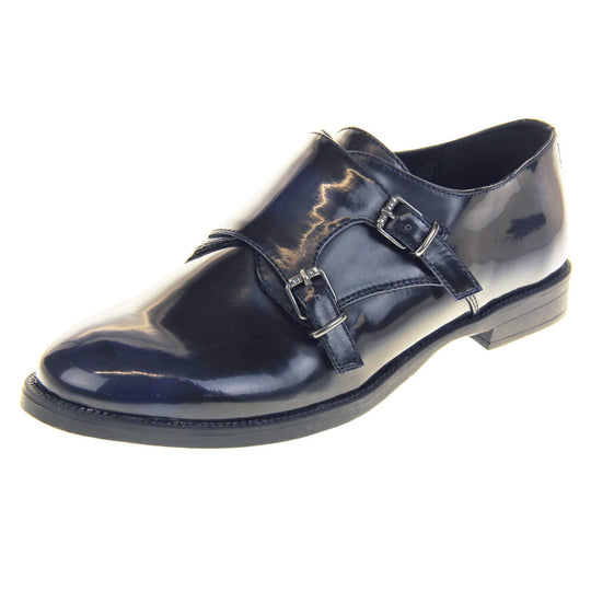 Womens leather brogues. Loafer shoes in a Brogue style with a dark blue faux leather upper. Faux leather flap over the top fastened with double buckles. Real leather lining. Black sole with a slight heel. Left foot at an angle.