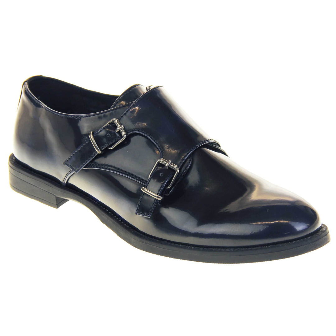 Womens leather brogues. Loafer shoes in a Brogue style with a dark blue faux leather upper. Faux leather flap over the top fastened with double buckles. Real leather lining. Black sole with a slight heel. Right foot at an angle.
