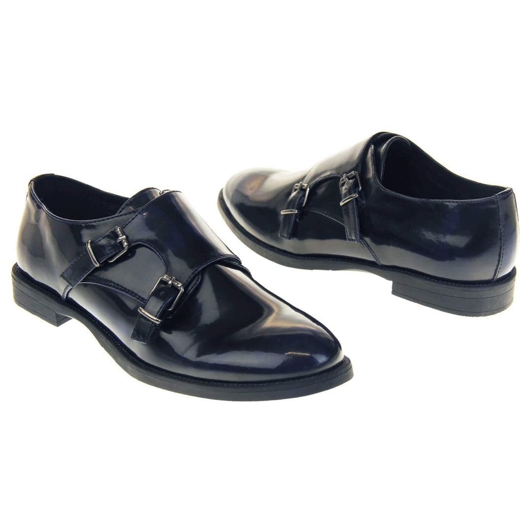 Womens leather brogues. Loafer shoes in a Brogue style with a dark blue faux leather upper. Faux leather flap over the top fastened with double buckles. Real leather lining. Black sole with a slight heel. Both feet at an angle facing top to tail.