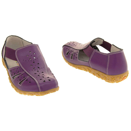 Womens leather sandals. Purple leather closed toe sandals with white stitched detailing. With small cut out details on the upper. Purple elasticated strips from tongue to ankle to allow more room for a better fit. Cream coloured leather insole and lining. Brown sole with heel having a slight platform with raised flower design for grip. Both feet at a slight angle facing top to tail.