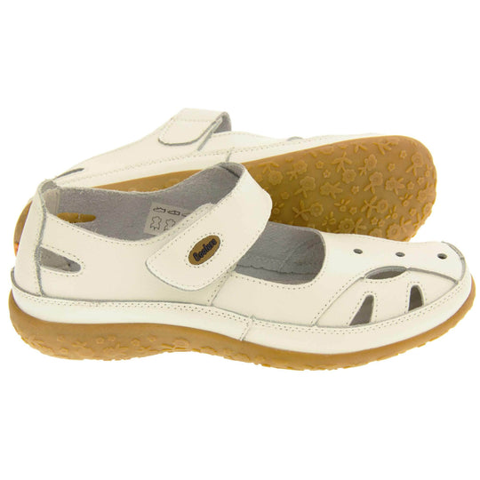 Womens leather shoes. Mary Jane style shoes. White leather uppers with white stitching detail. White touch fasten strap over the foot with brown oval, where it fastens, with Coolers logo in the centre. Cut outs in the middle, edges and heel of the shoes. Brown synthetic soles with flower design grips. Both feet from a side profile with left foot on its side behind the right to show the sole.