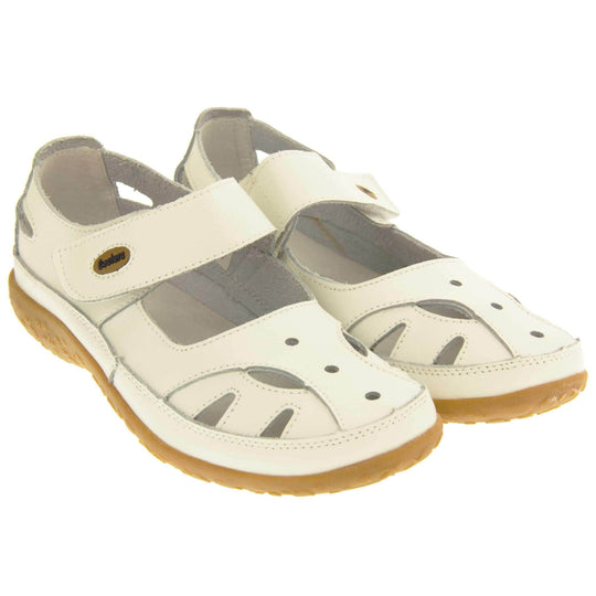 Womens leather shoes. Mary Jane style shoes. White leather uppers with white stitching detail. White touch fasten strap over the foot with brown oval, where it fastens, with Coolers logo in the centre. Cut outs in the middle, edges and heel of the shoes. Brown synthetic soles with flower design grips. Both shoes together from an angle