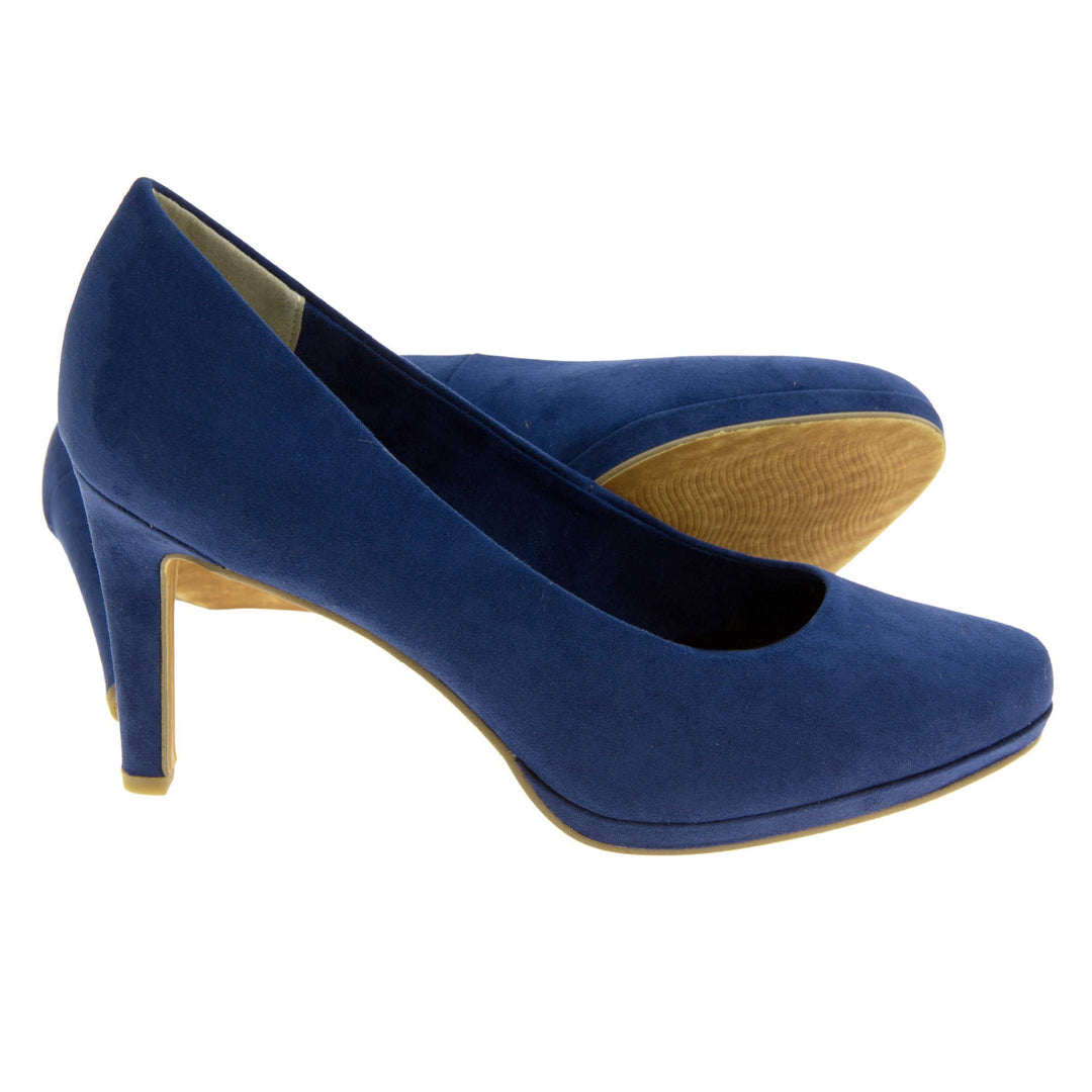 Womens navy court shoes.. Womens high heels with a faux suede navy blue upper. Cream insole with Marco Tozzi branding. Navy and beige faux suede lining. Navy faux suede mid stiletto heel. Brown sole. Both feet from a side profile with the left foot on its side behind the the right foot to show the sole.