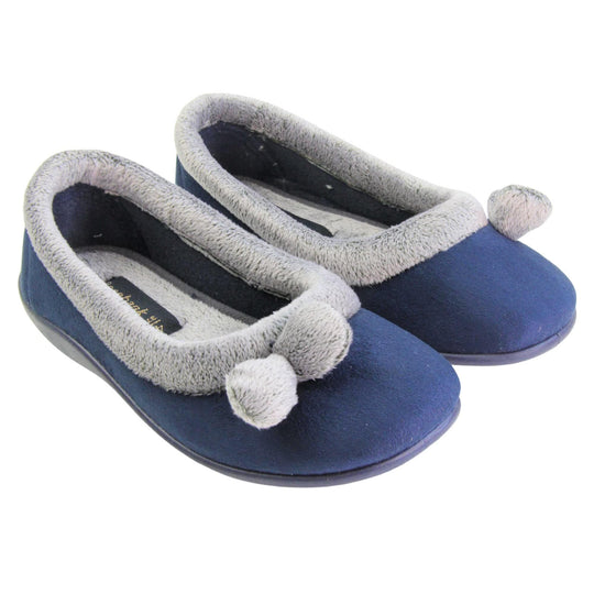 Womens navy slippers. Womens ballerina style slippers with navy blue velour uppers. Grey, plush textile collar and two pom poms to the front of the shoe. Matching textile lining. Firm navy sole. Both feet together at an angle.