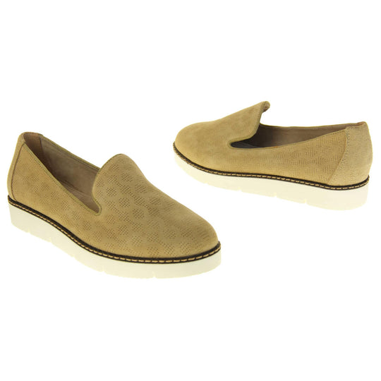Womens platform loafers. Loafer style shoes with a beige faux-suede upper with pin size dot cut-outs. Plain beige strip over the heel for added support. White flat chunky platform outsole with black rim along the top and beige stitching detail. Cream leather lining. Both feet at an angle facing top to tail.