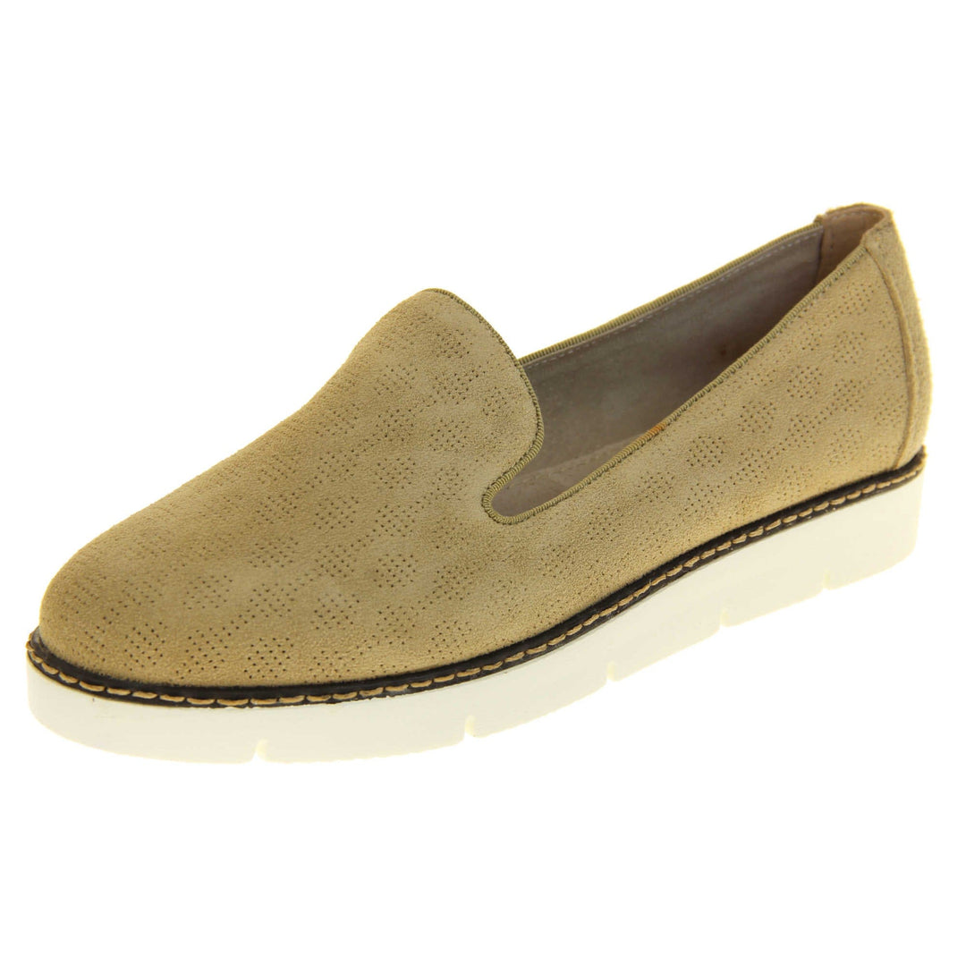Womens platform loafers. Loafer style shoes with a beige faux-suede upper with pin size dot cut-outs. Plain beige strip over the heel for added support. White flat chunky platform outsole with black rim along the top and beige stitching detail. Cream leather lining. Left foot at an angle.