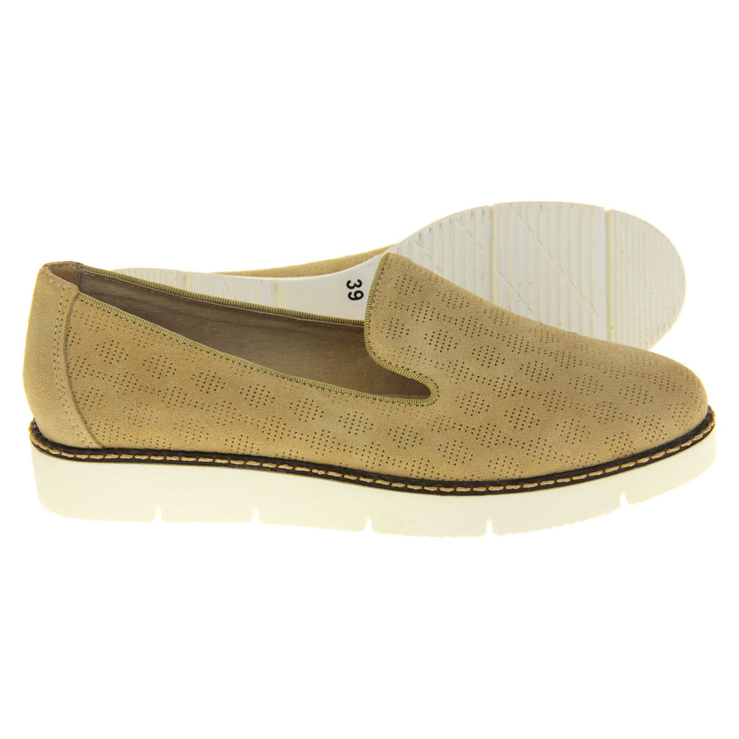 Womens platform loafers. Loafer style shoes with a beige faux-suede upper with pin size dot cut-outs. Plain beige strip over the heel for added support. White flat chunky platform outsole with black rim along the top and beige stitching detail. Cream leather lining. Both feet from a side profile with the left foot on its side behind the the right foot to show the sole.