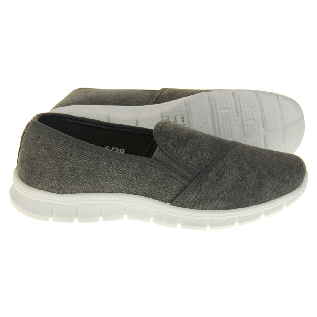 Women's plimsolls grey. Slip on plimsoll style shoes with a grey canvas upper. Grey elasticated gusset. Chunky white sole. Both feet from a side profile with the left foot on its side behind the the right foot to show the sole.