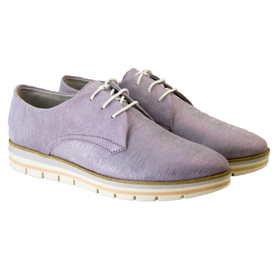 Womens purple dress shoes. Womens oxford style shoes with a lavender metallic faux leather upper. Stitching detail to the sides. Cream laces and beige lining and cream, orange and lilac layered platform sole. Both feet together at a slight angle.