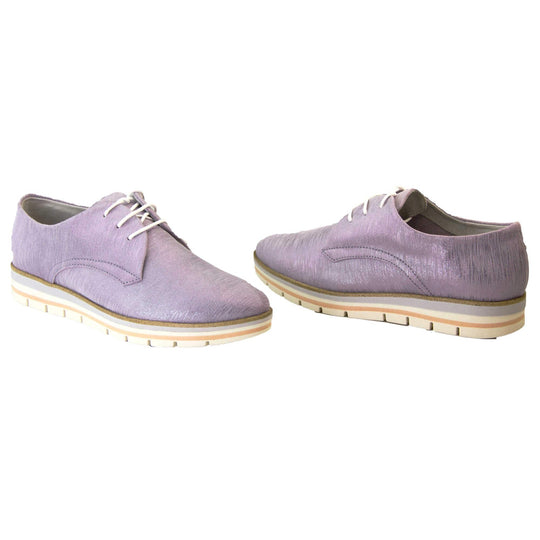 Womens purple dress shoes. Womens oxford style shoes with a lavender metallic faux leather upper. Stitching detail to the sides. Cream laces and beige lining and cream, orange and lilac layered platform sole. Both feet at an angle facing top to tail.