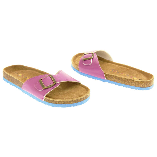 Womens purple sandals. Purple faux leather strap with gold buckle. Soft tan faux suede footbed with cork effect outsole and blue sole. Both feet at an angle facing top to tail.