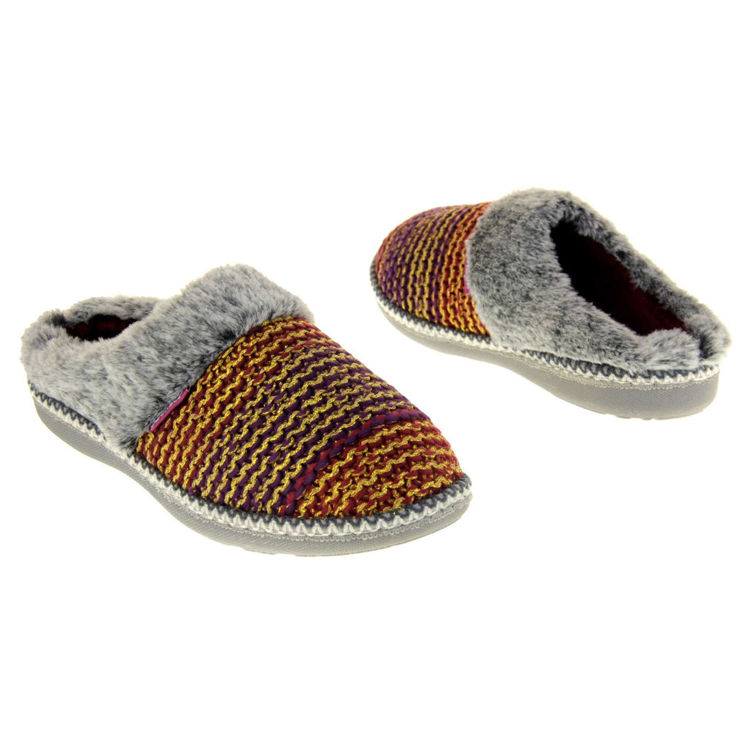 Womens purple slippers. Mule style slippers with purple and red knit uppers with metallic gold thread running through. Grey faux fur collar. Red textile lining and firm grey outsole with grip on the bottom. Both feet at an angle, facing top to tail.