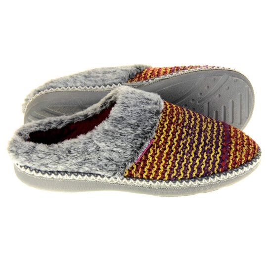 Womens purple slippers. Mule style slippers with purple and red knit uppers with metallic gold thread running through. Grey faux fur collar. Red textile lining and firm grey outsole with grip on the bottom. Both feet from a side profile with the left foot on its side behind the the right foot to show the sole.
