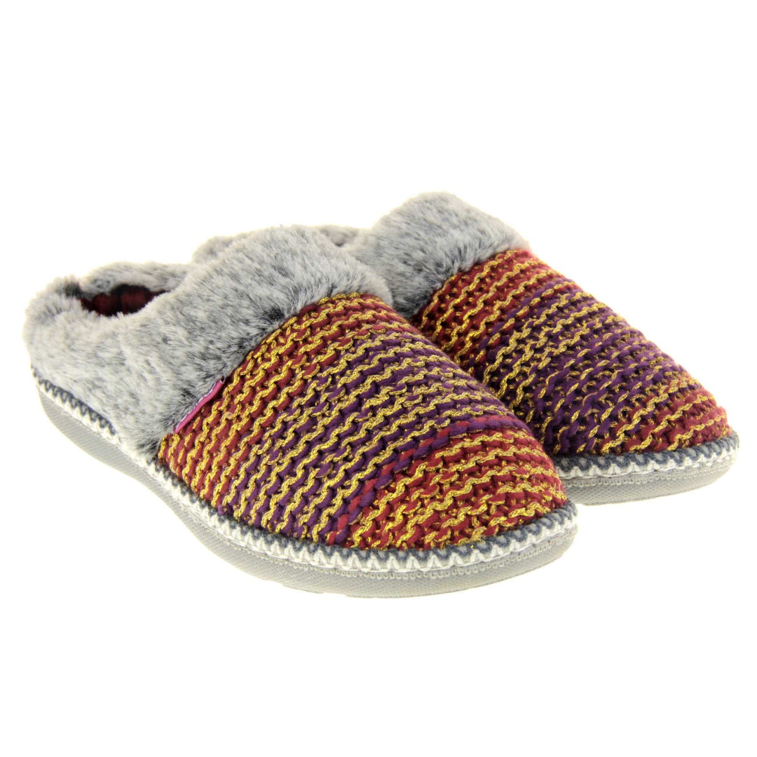 Womens purple slippers. Mule style slippers with purple and red knit uppers with metallic gold thread running through. Grey faux fur collar. Red textile lining and firm grey outsole with grip on the bottom. Both feet together at an angle.