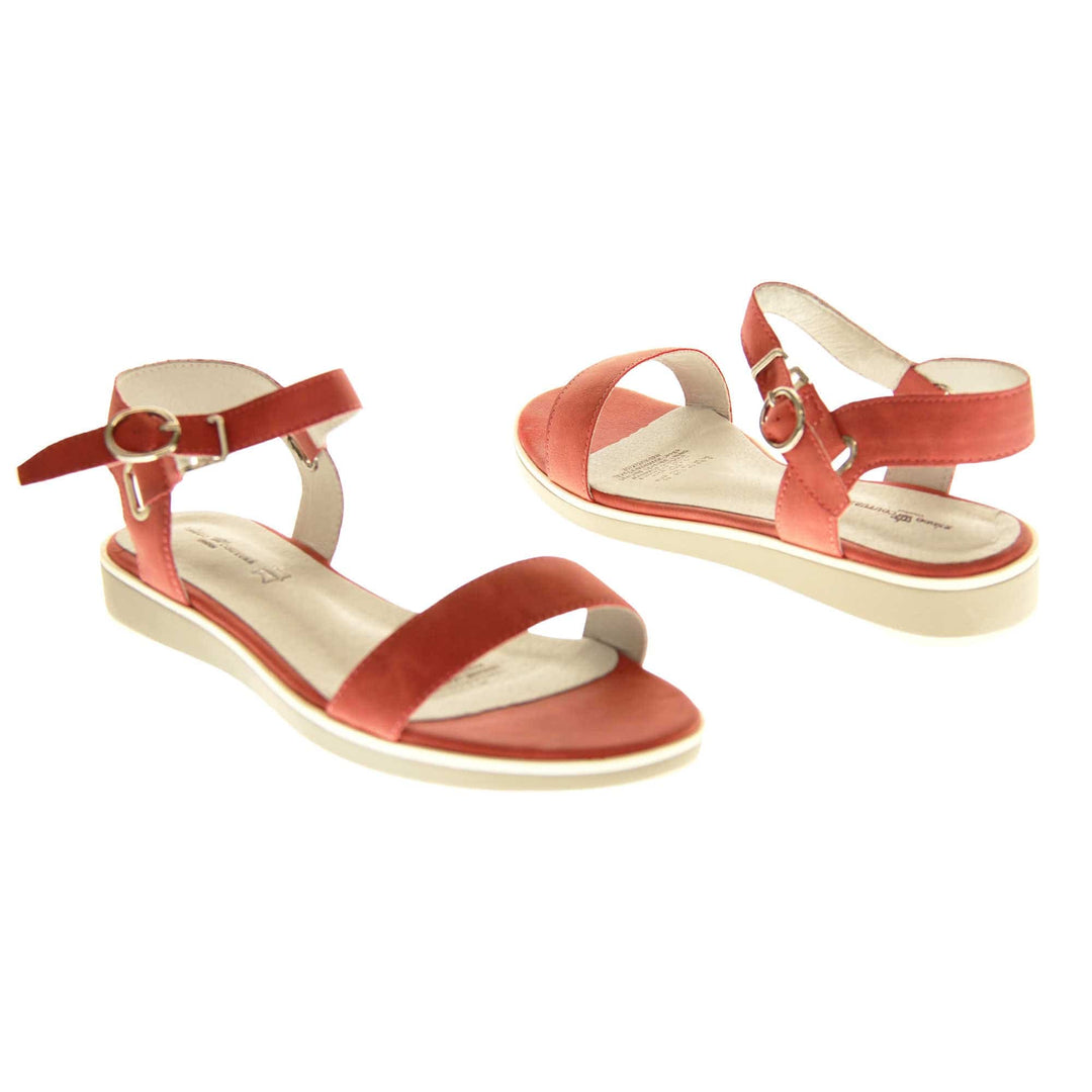 Womens red flat sandals. Classic womens strappy sandals with red faux leather straps around the ankle and over the toes. The ankle strap has a gold buckle fastening. Beige faux leather cushioned insoles. Very small wedge heel with beige outsole with a white rim around the top. Both shoes about an inch apart at a slight angle facing top to tail.