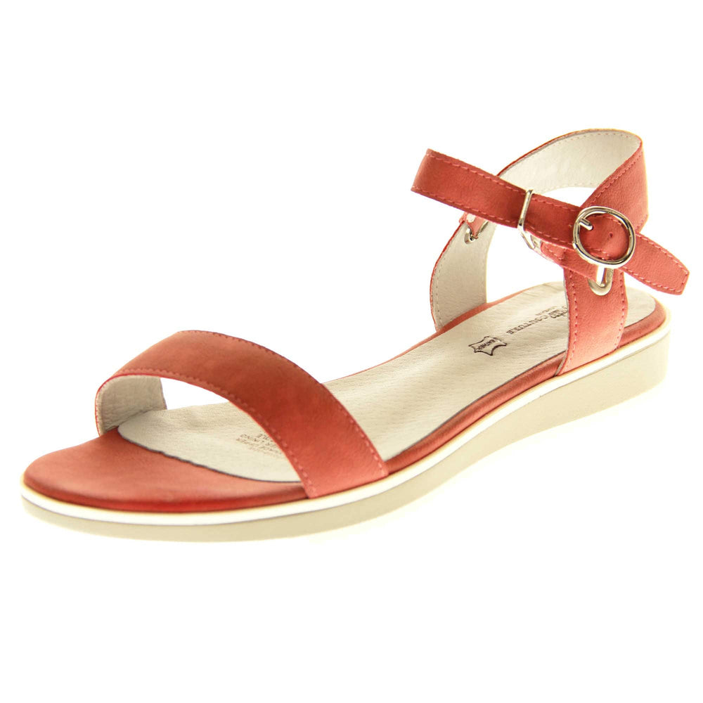 Womens red flat sandals. Classic womens strappy sandals with red faux leather straps around the ankle and over the toes. The ankle strap has a gold buckle fastening. Beige faux leather cushioned insoles. Very small wedge heel with beige outsole with a white rim around the top. Left foot at an angle.