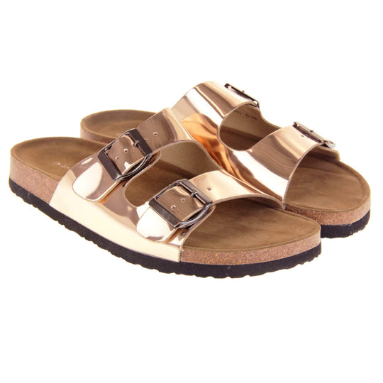 Womens rose gold sandals. Ladies dual strap slip on sandals. With a metallic rose gold synthetic leather upper with a pewter buckle on each strap. Brown faux suede insole with a moulded footbed. Cork effect outsole with black base with grip to the bottom. Both feet together at a slight angle.