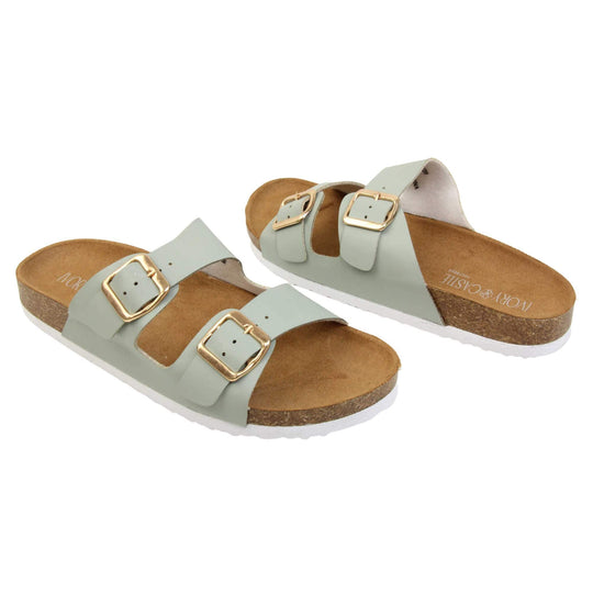 Womens sage sandals. Womens dual strap slip on sandals. With a sage green synthetic leather upper with a gold buckle on each strap. Brown faux suede insole with a moulded footbed. Cork effect outsole with white base with grip to the bottom. Both feet at an angle facing top to tail.
