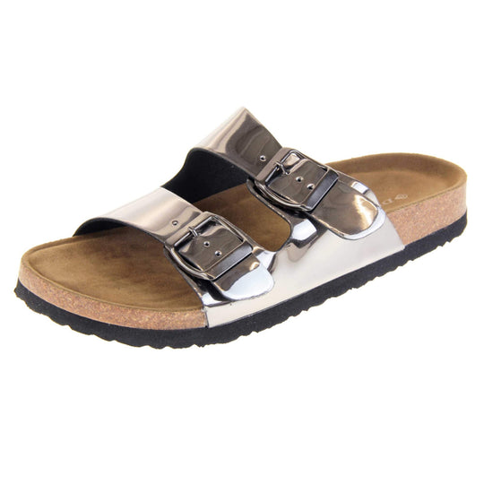 Womens silver sandals. Ladies dual strap slip on sandals. With a metallic pewter synthetic leather upper and pewter buckle on each strap. Brown faux suede insole with a moulded footbed. Cork effect outsole with black base with grip to the bottom. Left foot at an angle.