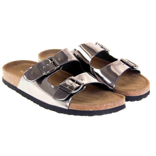Womens silver sandals. Ladies dual strap slip on sandals. With a metallic pewter synthetic leather upper and pewter buckle on each strap. Brown faux suede insole with a moulded footbed. Cork effect outsole with black base with grip to the bottom. Both feet together at a slight angle.