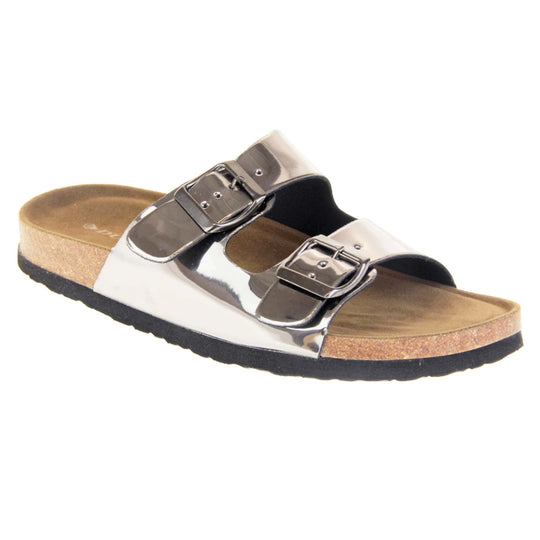Womens silver sandals. Ladies dual strap slip on sandals. With a metallic pewter synthetic leather upper and pewter buckle on each strap. Brown faux suede insole with a moulded footbed. Cork effect outsole with black base with grip to the bottom. Right foot at an angle.