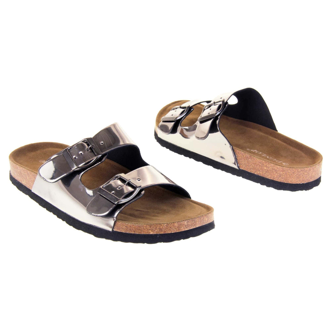 Womens silver sandals. Ladies dual strap slip on sandals. With a metallic pewter synthetic leather upper and pewter buckle on each strap. Brown faux suede insole with a moulded footbed. Cork effect outsole with black base with grip to the bottom. Both feet at an angle facing top to tail.