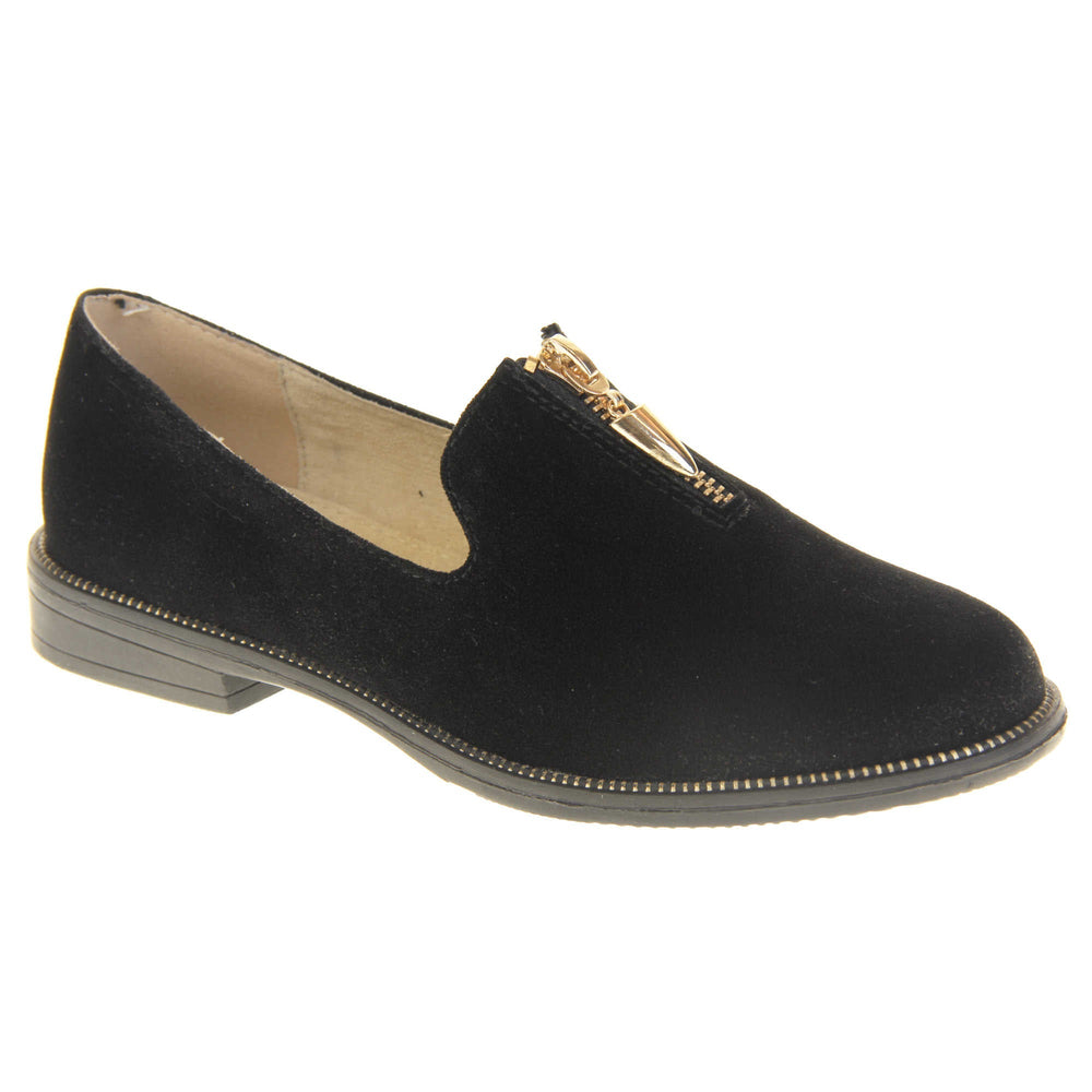 Womens smart loafers. Loafer style shoes with black faux suede uppers. Short gold zip detail to the top of the shoe. Gold stud detail around the rim of the sole. Black sole with very small heel and beige leather lining. Right foot at an angle.