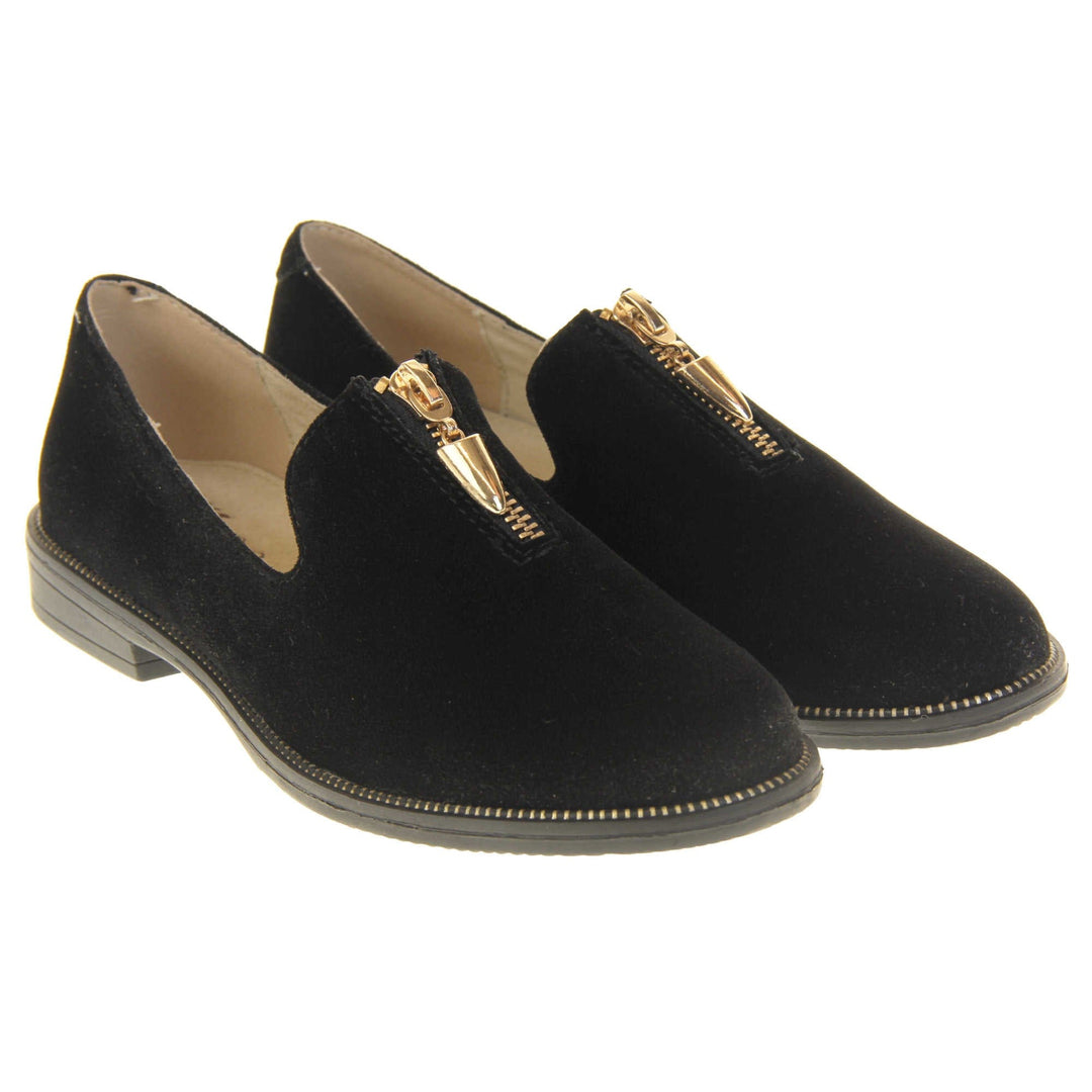 Womens smart loafers. Loafer style shoes with black faux suede uppers. Short gold zip detail to the top of the shoe. Gold stud detail around the rim of the sole. Black sole with very small heel and beige leather lining. Left foot at an angle. Both feet together at an angle.