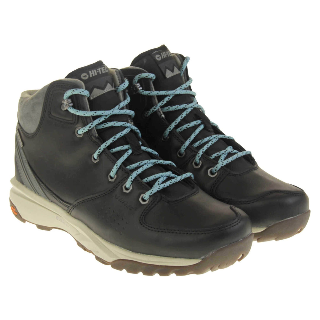 Womens walking boots. Black leather walking boots with grey soles of the side, black soles on the bottom. Deep grip on the base. Pale blue laces to the front with Hi-Tec branding in grey on the tongue. Grey velour padded collar for ankles. Both feet together at an angle