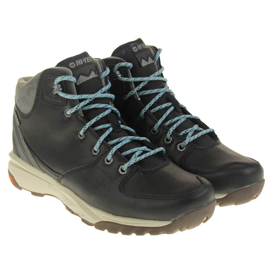 Womens walking boots. Black leather walking boots with grey soles of the side, black soles on the bottom. Deep grip on the base. Pale blue laces to the front with Hi-Tec branding in grey on the tongue. Grey velour padded collar for ankles. Both feet together at an angle