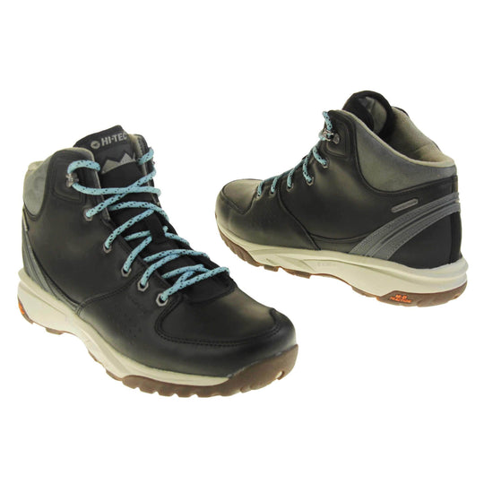 Womens walking boots. Black leather walking boots with grey soles of the side, black soles on the bottom. Deep grip on the base. Pale blue laces to the front with Hi-Tec branding in grey on the tongue. Grey velour padded collar for ankles. Both feet top to tail at an angle.