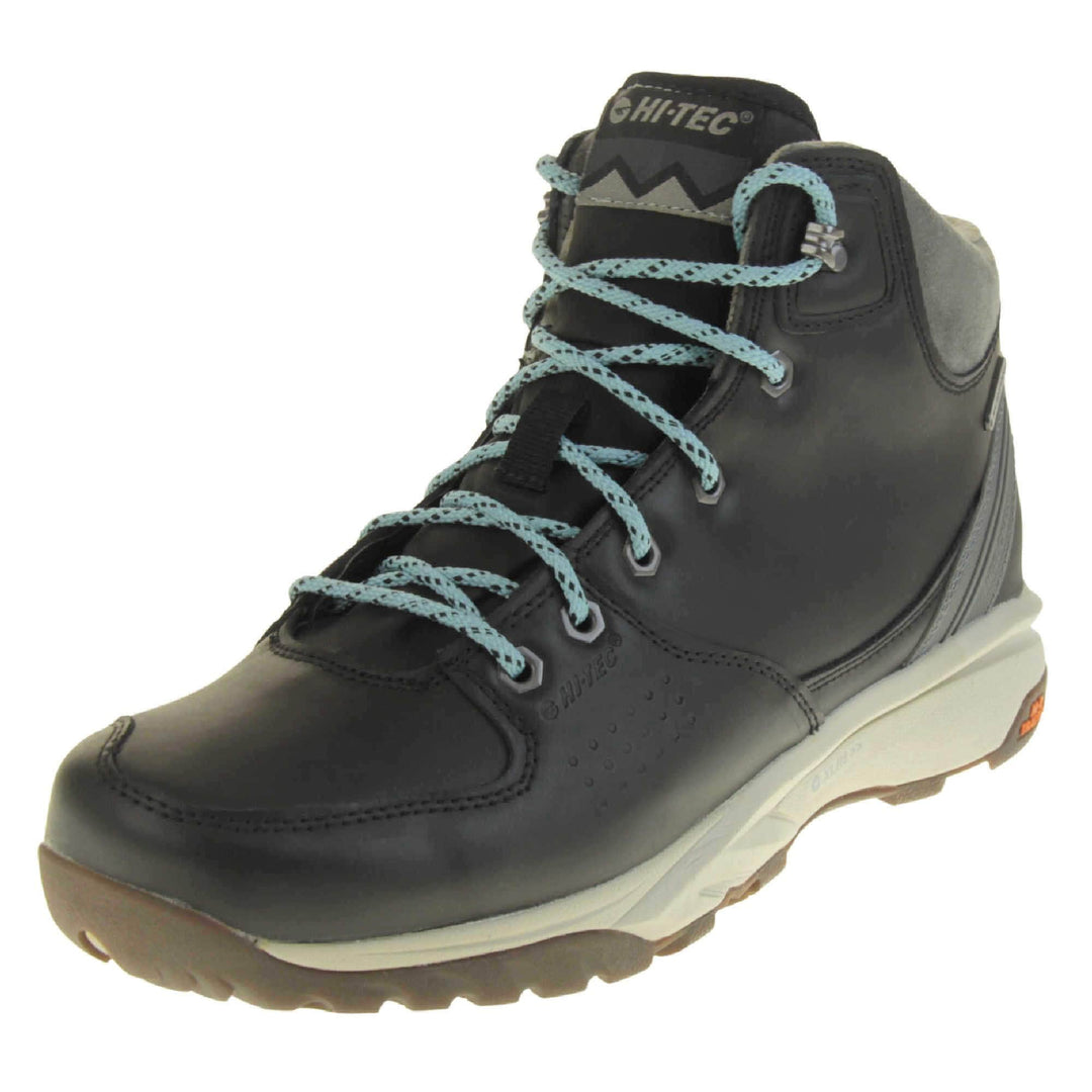 Womens walking boots. Black leather walking boots with grey soles of the side, black soles on the bottom. Deep grip on the base. Pale blue laces to the front with Hi-Tec branding in grey on the tongue. Grey velour padded collar for ankles. Left foot at an angle