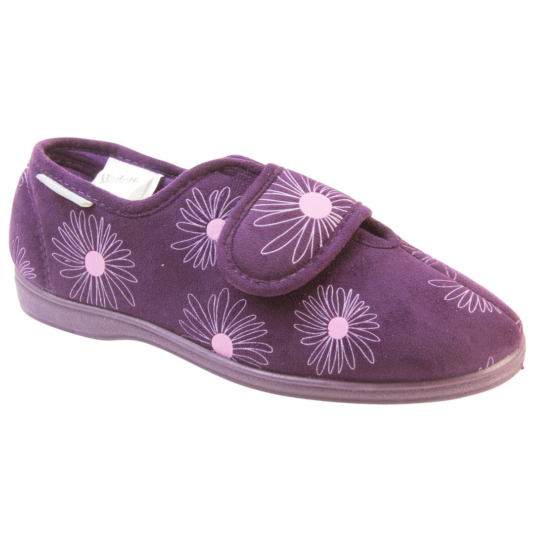 Womens washable slippers. Ladies full back slipper. Purple upper with white daisy design and bright pink for the middle of the flowers. Touch fasten strap over the top of the foot to adjust the fit. Matching purple textile lining and firm purple sole. Right foot at an angle.