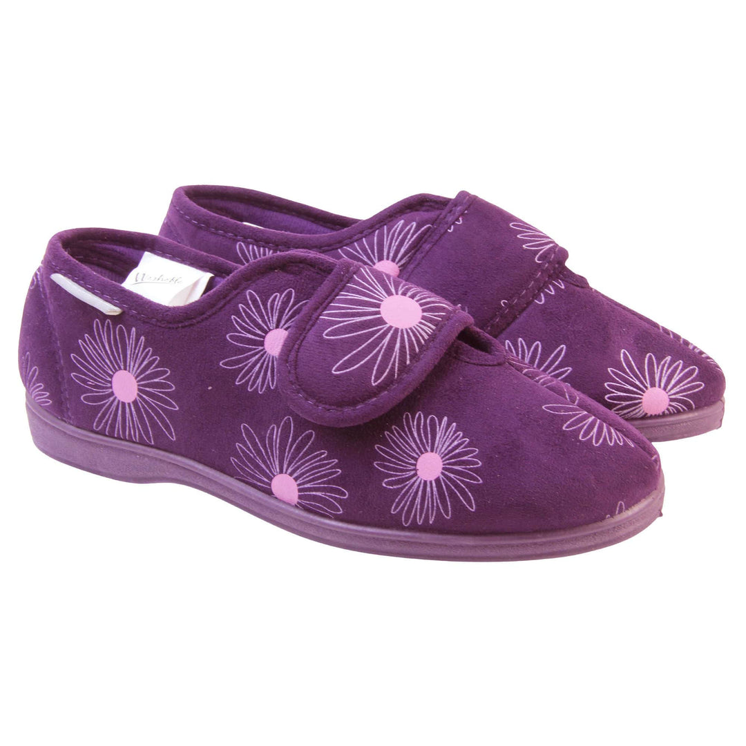 Womens washable slippers. Ladies full back slipper. Purple upper with white daisy design and bright pink for the middle of the flowers. Touch fasten strap over the top of the foot to adjust the fit. Matching purple textile lining and firm purple sole. Both feet together at an angle.