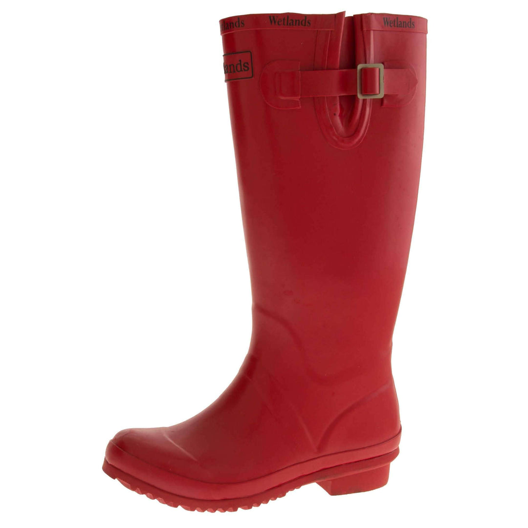 Womens Wellies. Red rubber waterproof wellington boots. Just below knee height. With a small heel and deep tread to the sole. Black Wetlands Brand to the front of the boot near the top. Wetlands written in black numerous times around the rim of the boot. Side strap with buckle to adjust the calf width. Textile lining to the inside of the boot. Left foot at an angle.