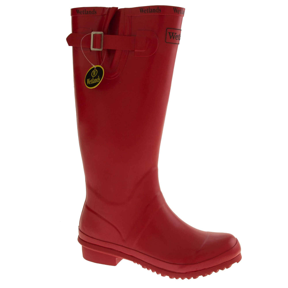 Womens Wellies. Red rubber waterproof wellington boots. Just below knee height. With a small heel and deep tread to the sole. Black Wetlands Brand to the front of the boot near the top. Wetlands written in black numerous times around the rim of the boot. Side strap with buckle to adjust the calf width. Textile lining to the inside of the boot. Right foot at an angle.