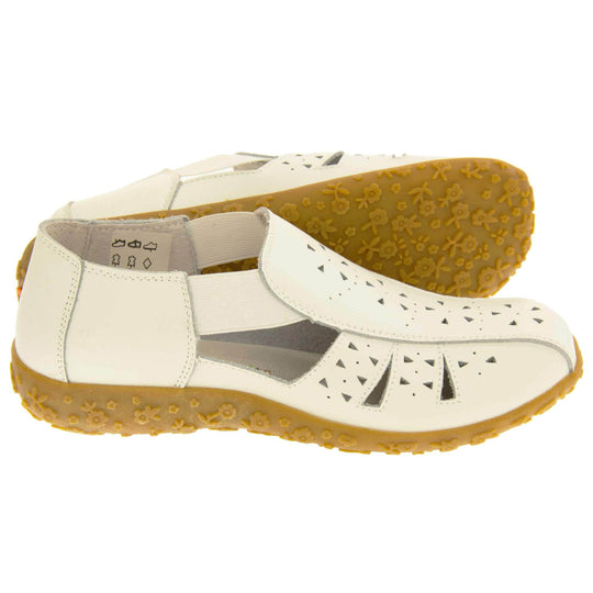 Womens white sandals. White leather closed toe sandals with white stitched detailing. With small cut out details on the upper. White elasticated strips from tongue to ankle to allow more room for a better fit. Cream coloured leather insole and lining. Brown sole with heel having a slight platform with raised flower design for grip. Both feet from side profile with left foot on its side behind the right to show the sole.