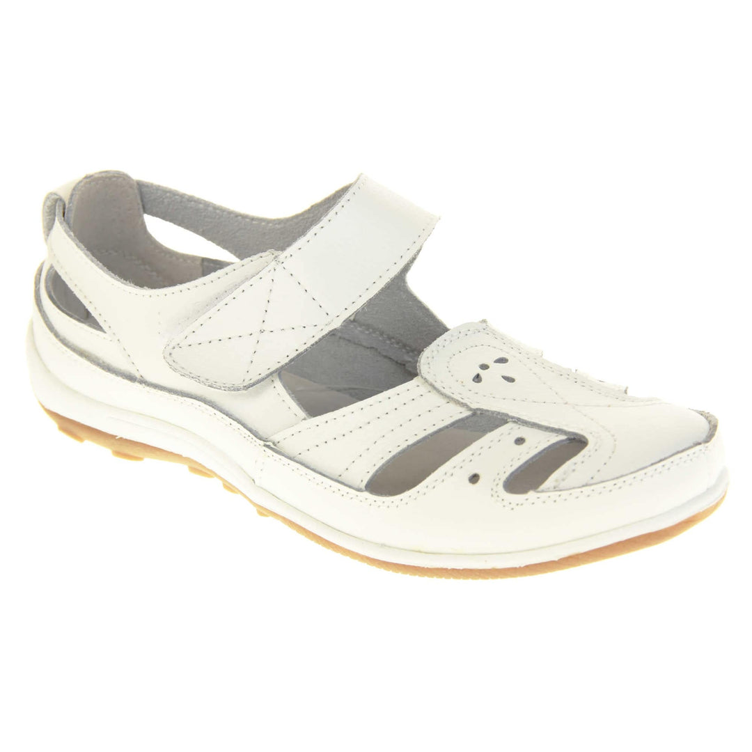 Womens white strap sandals. Mary Jane style shoes. White leather uppers with white stitching detail. White touch fasten strap over the foot. Cut outs in the middle, edges and heel of the shoes. Beige sole with grip to the bottom. Right foot at an angle.