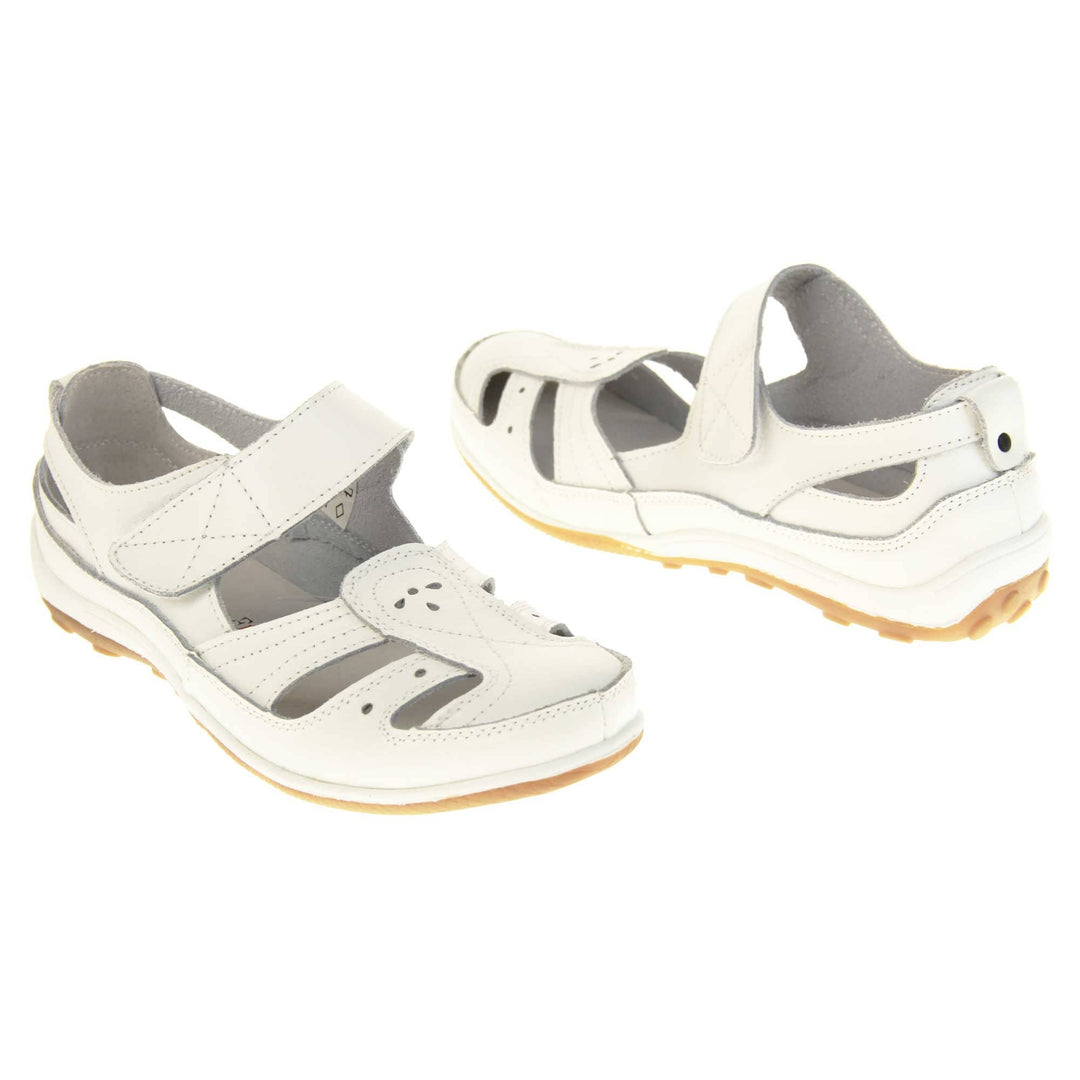 Womens white strap sandals. Mary Jane style shoes. White leather uppers with white stitching detail. White touch fasten strap over the foot. Cut outs in the middle, edges and heel of the shoes. Beige sole with grip to the bottom. Both shoes about an inch apart at a slight angle facing top to tail.