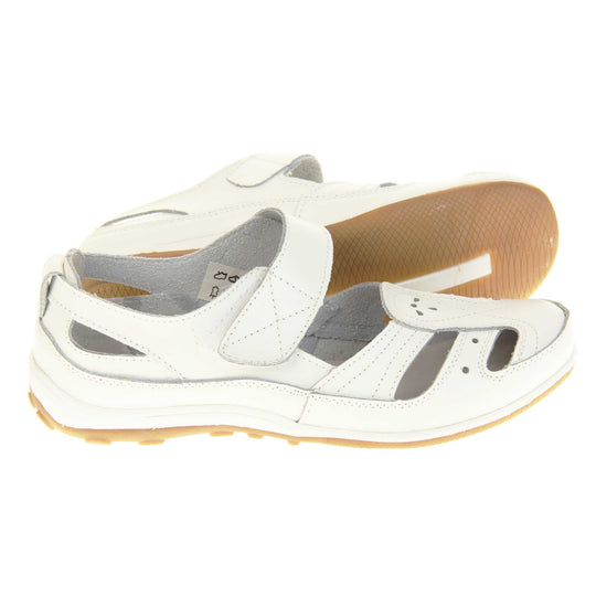 Womens white strap sandals. Mary Jane style shoes. White leather uppers with white stitching detail. White touch fasten strap over the foot. Cut outs in the middle, edges and heel of the shoes. Beige sole with grip to the bottom. Both feet from a side profile with left foot on its side behind the right to show the sole.