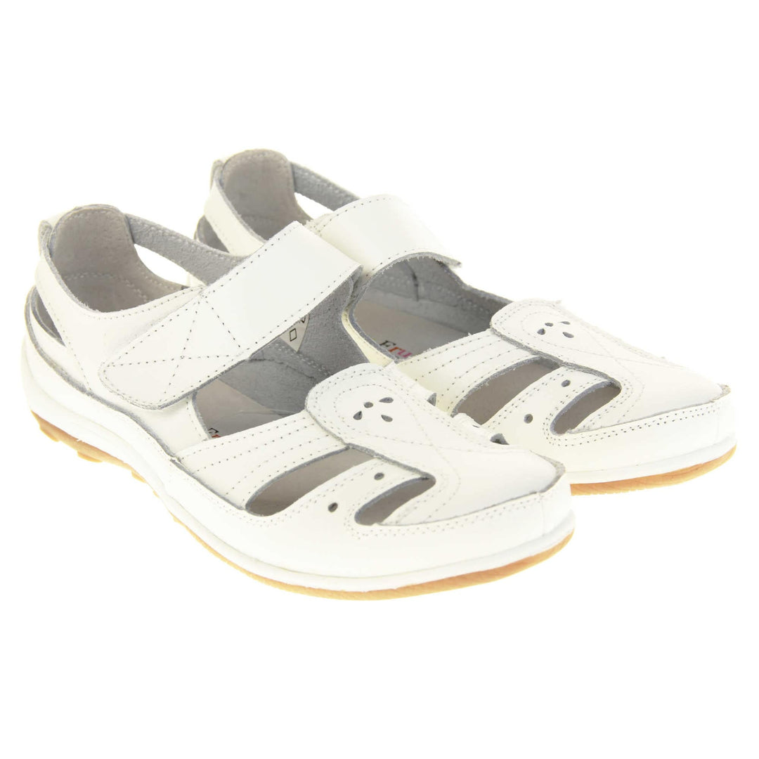 Womens white strap sandals. Mary Jane style shoes. White leather uppers with white stitching detail. White touch fasten strap over the foot. Cut outs in the middle, edges and heel of the shoes. Beige sole with grip to the bottom. Both shoes together from an angle