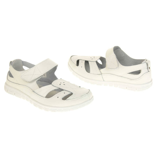 Womens white wide fit sandals. Mary Jane style shoes. White leather uppers with white stitching detail. White touch fasten strap over the foot. Cut outs in the middle, edges and heel of the shoes. White sole with grip to the bottom.  Both shoes about an inch apart at a slight angle facing top to tail.