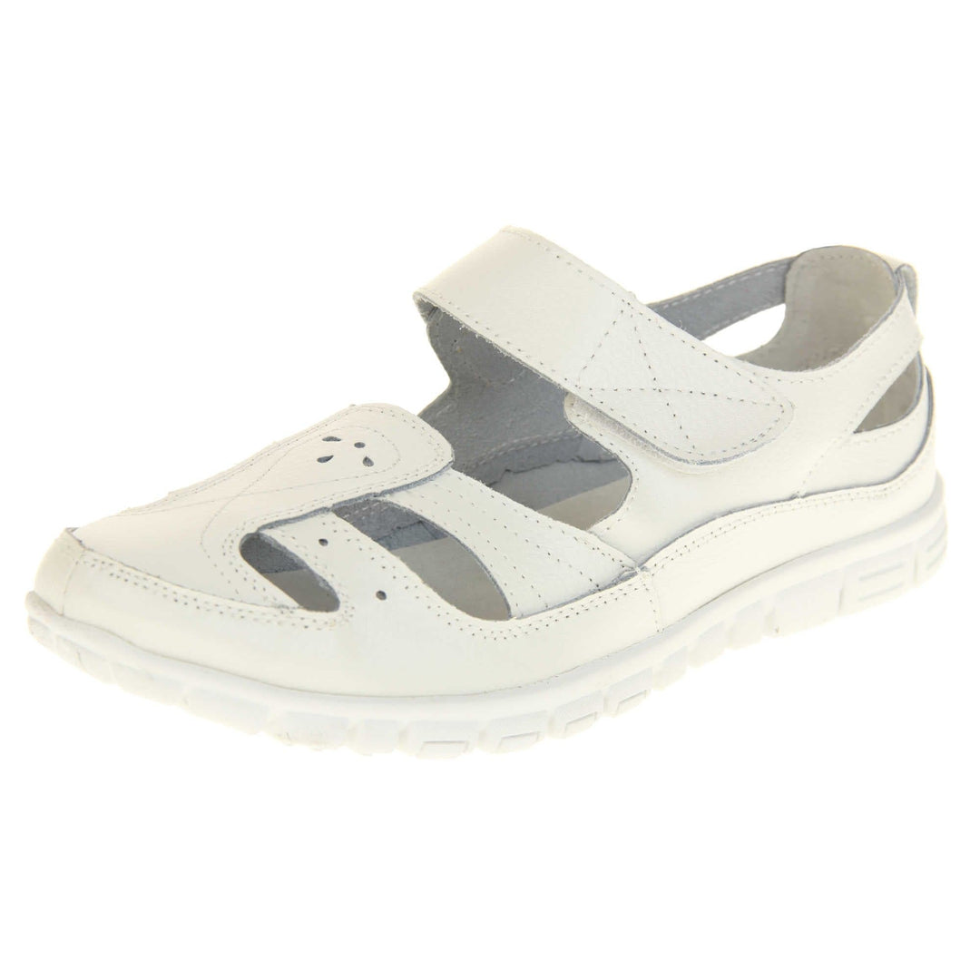 Womens white wide fit sandals. Mary Jane style shoes. White leather uppers with white stitching detail. White touch fasten strap over the foot. Cut outs in the middle, edges and heel of the shoes. White sole with grip to the bottom. Left foot at an angle.