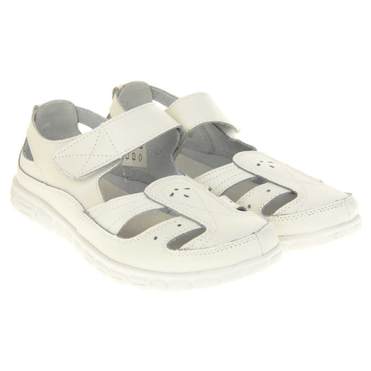 Womens white wide fit sandals. Mary Jane style shoes. White leather uppers with white stitching detail. White touch fasten strap over the foot. Cut outs in the middle, edges and heel of the shoes. White sole with grip to the bottom. Both shoes together from an angle