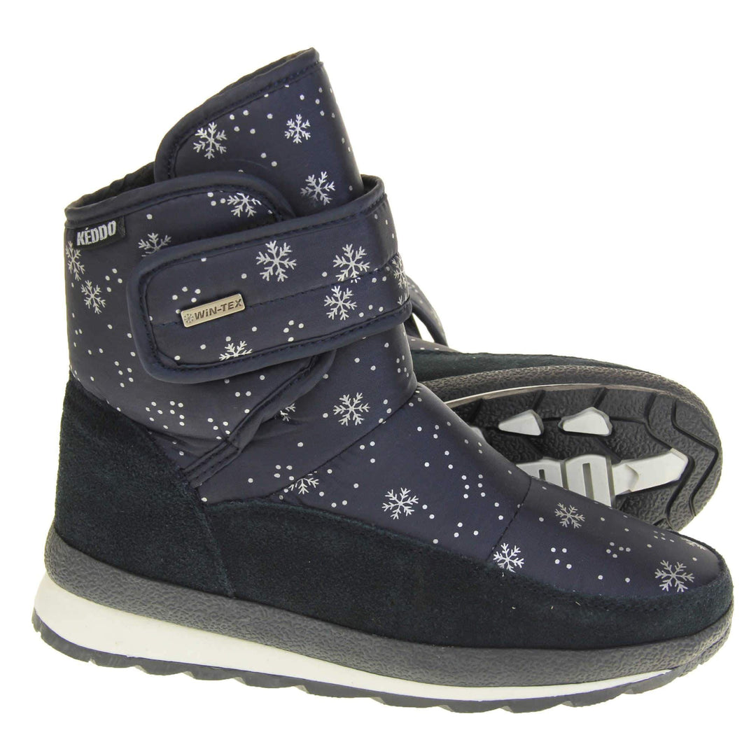 Womens Winter Boots. Navy blue textile upper with snowflake and dots pattern on in white. Dark blue faux-suede edging to the bottom of the boot . Grey and white chunky sole with good grip. Faux fur lining. Silver metal Win-Tex tag on the touch fasten strap, Keddo label along outside rim of the foot. Both shoes from side profile with left shoe on its side so you can see the sole.